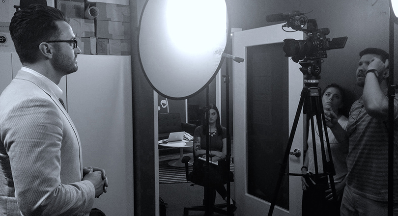Black and white image of man speaking infront of camera