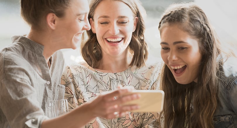 3 people looking at phone smiling