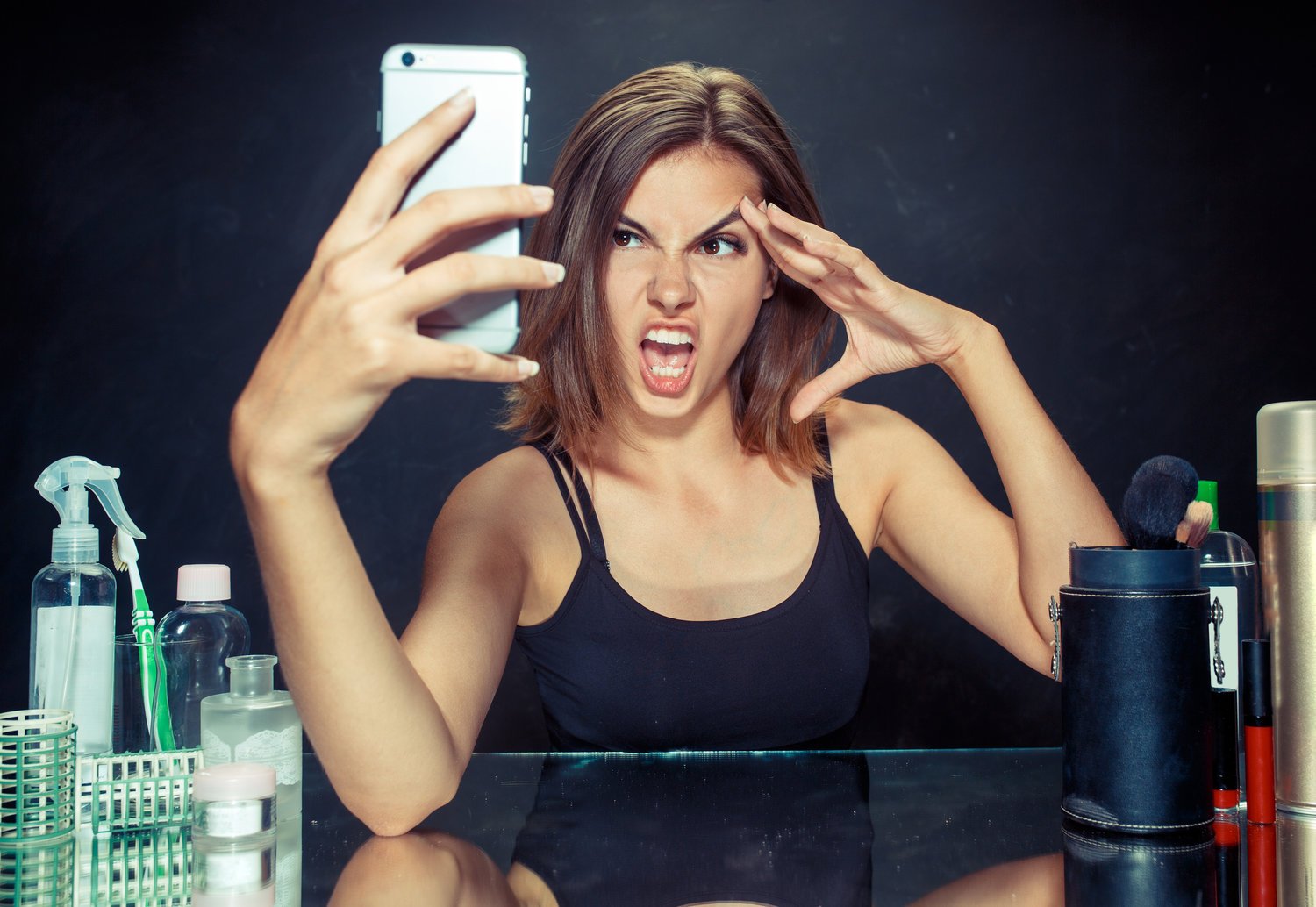 girl looking into phone and mirror