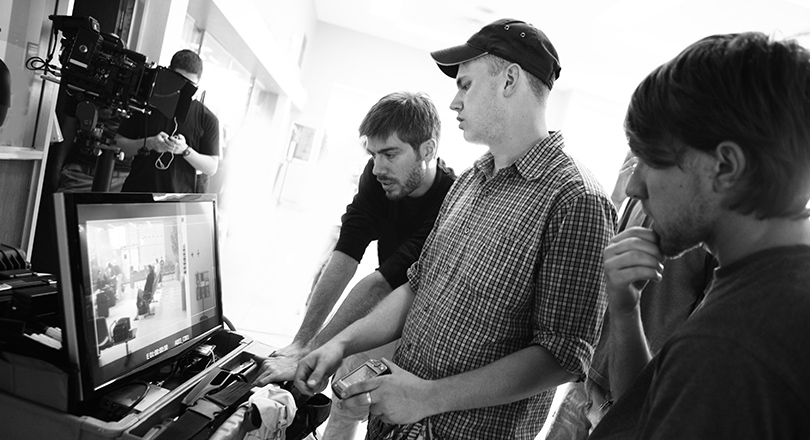 black and white image of men looking at screen